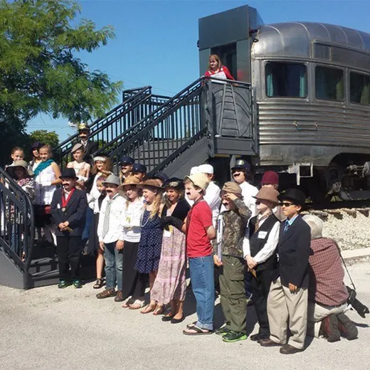 Guests in period costume beside a historic rail car
