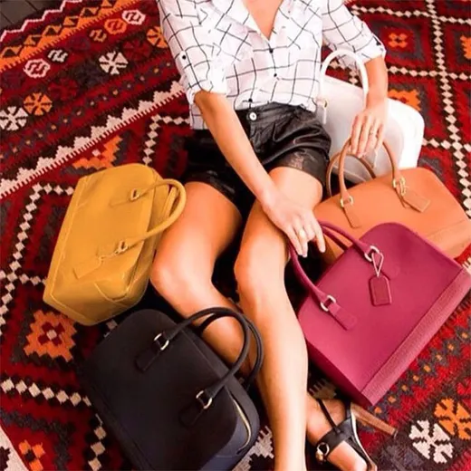 Designer handbags styled on a patterned rug